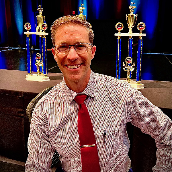 Photo of Dr. Gregory W. Lefils, Jr., trophies on display in the background.