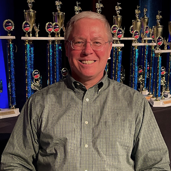 Photo of Dr. John A. Lychner, trophies on display in the background.