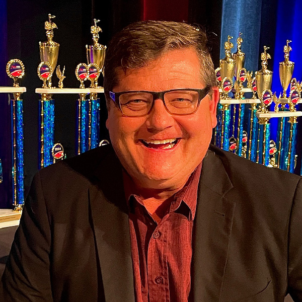 Photo of Dr. Timothy Peter, trophies on display in the background.