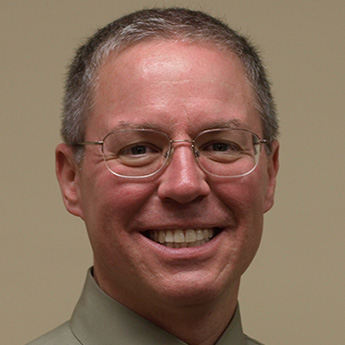 Photo of Dr. John A. Lychner, trophies on display in the background.
