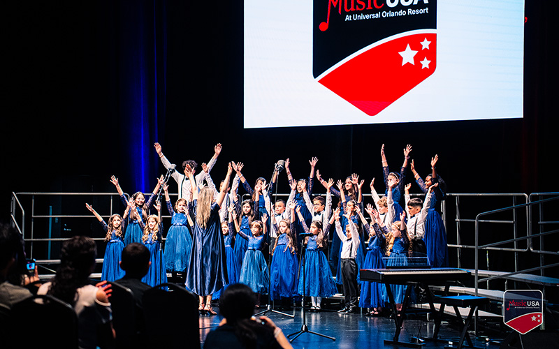young performers on stage with their hands up